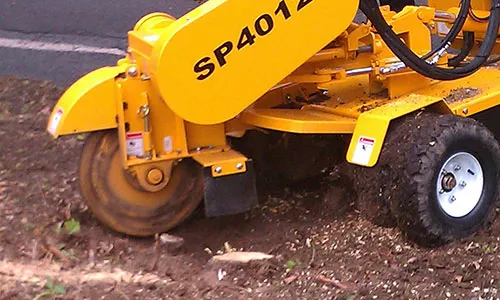 A yellow machine is on the ground near some dirt.